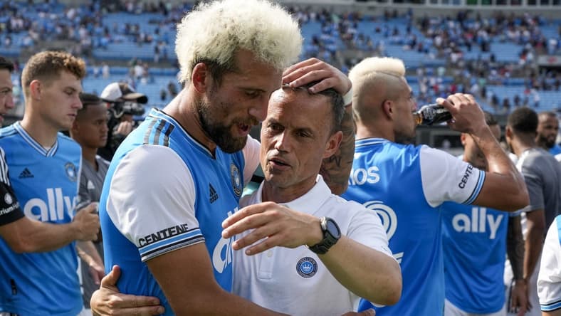 Jun 11, 2022; Charlotte, North Carolina, USA; Interim Charlotte FC head coach Christian Lattanzio and defender Guzm n Corujo (4) celebrate the home win over the New York Red Bulls at Bank of America Stadium. Mandatory Credit: Jim Dedmon-USA TODAY Sports