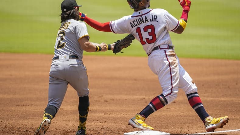 Jun 12, 2022; Cumberland, Georgia, USA; Atlanta Braves right fielder Ronald Acuna Jr. (13) gets back to first base ahead of the tag by Pittsburgh Pirates first baseman Michael Chavis (2) during the first inning at Truist Park. Mandatory Credit: Dale Zanine-USA TODAY Sports