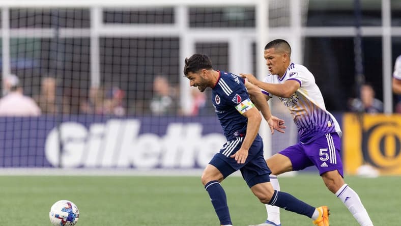 Jun 15, 2022; Foxborough, Massachusetts, USA; Orlando City SC midfielder Cesar Araujo (5) defends New England Revolution midfielder Carles Gil (10) during the first half at Gillette Stadium. Mandatory Credit: Paul Rutherford-USA TODAY Sports