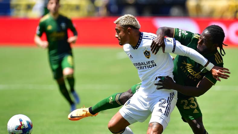 Jun 18, 2022; Carson, California, USA; Los Angeles Galaxy defender Julian Araujo (2) plays for the ball against Portland Timbers forward Yimmi Chara (23) during the first half at Dignity Health Sports Park. Mandatory Credit: Gary A. Vasquez-USA TODAY Sports