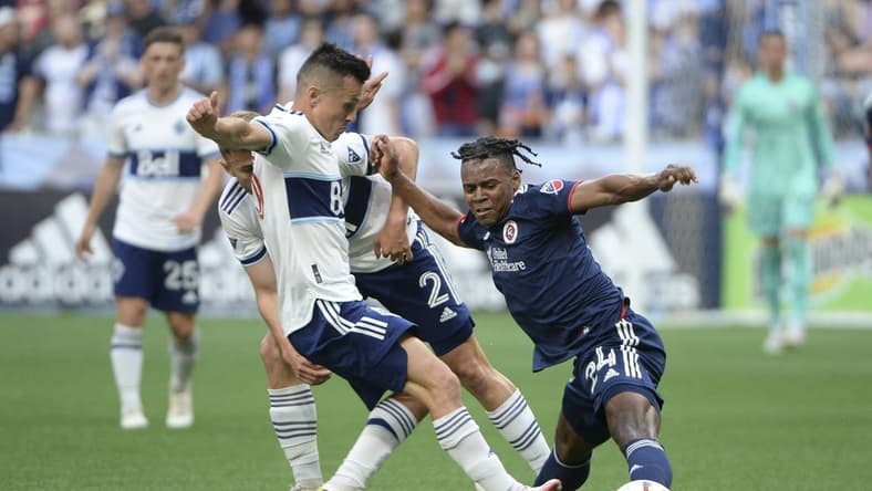 Jun 26, 2022; Vancouver, British Columbia, CAN;  New England Revolution forward DeJuan Jones (24) reaches for the ball against Vancouver Whitecaps defender Marcus Godinho (2) during the first half at BC Place. Mandatory Credit: Anne-Marie Sorvin-USA TODAY Sports