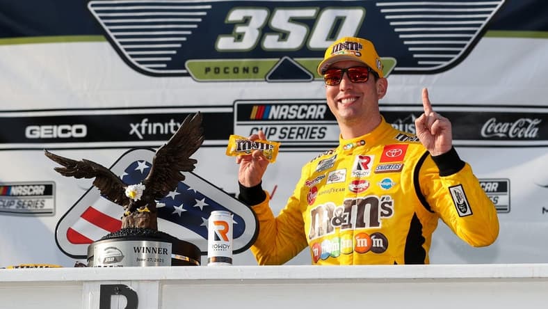 Jun 27, 2021; Long Pond, Pennsylvania, USA; NASCAR Cup Series driver Kyle Busch (18) celebrates in victory lane after winning the Explore the Pocono Mountains 350 at Pocono Raceway. Mandatory Credit: Matthew OHaren-USA TODAY Sports