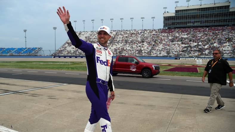 Jun 26, 2022; Nashville, Tennessee, USA; NASCAR Cup Series driver Denny Hamlin (11) waves to fans as he makes his way back to his car following a weather delay during the Ally 400 at Nashville Superspeedway. Mandatory Credit: Christopher Hanewinckel-USA TODAY Sports