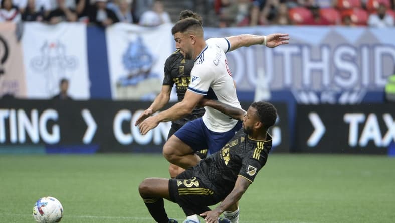 Jul 2, 2022; Vancouver, British Columbia, CAN;  Los Angeles FC midfielder Kellyn Acosta (23) collides with Vancouver Whitecaps forward Lucas Cavallini (9) during the first half at BC Place. Mandatory Credit: Anne-Marie Sorvin-USA TODAY Sports