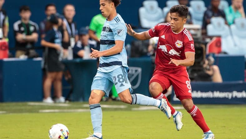 Jul 3, 2022; Kansas City, Kansas, USA; Sporting Kansas City midfielder Cameron Duke (28) drives the ball away from New York Red Bulls midfielder Frankie Amaya (8) during the first half at Children's Mercy Park. Mandatory Credit: William Purnell-USA TODAY Sports