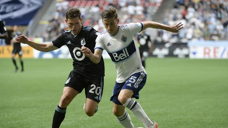Jul 8, 2022; Vancouver, British Columbia, CAN; Vancouver Whitecaps FC midfielder Ryan Gauld (25) controls the ball against Minnesota United FC midfielder Will Trapp (20) during the first half at BC Place. Mandatory Credit: Anne-Marie Sorvin-USA TODAY Sports