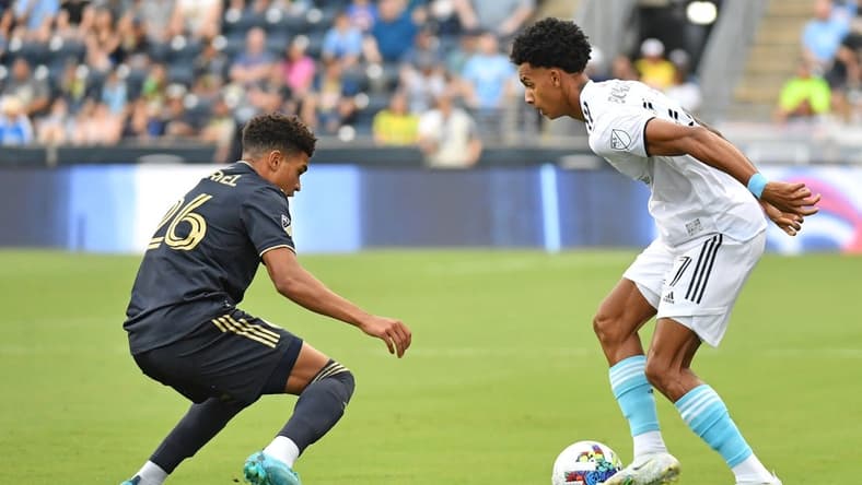 Jul 16, 2022; Chester, Pennsylvania, USA; New England Revolution midfielder Dylan Borrero (27) is defended by Philadelphia Union defender Nathan Harriel (26) during the first half at Subaru Park. Mandatory Credit: Eric Hartline-USA TODAY Sports