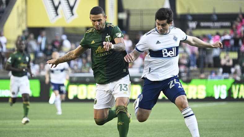 Jul 17, 2022; Portland, Oregon, USA; Portland Timbers defender Dario Zuparic (13) defends Vancouver Whitecaps forward Brian White (24) during the first half at Providence Park. Mandatory Credit: Troy Wayrynen-USA TODAY Sports