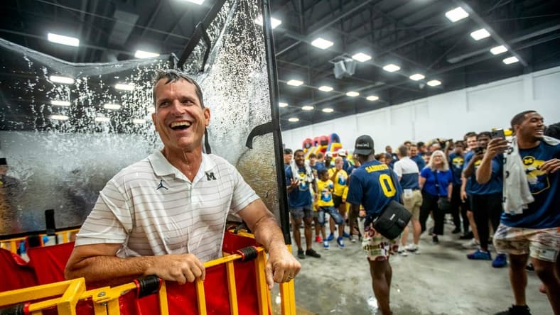 Michigan head coach Jim Harbaugh reacts after being knocked into a dunk tank for the first time during the Maize and Blue Big Top Event Kids Fair at the Dort Event Center in Flint on Thursday, July 21, 2022, as part of the Michigan football state caravan.