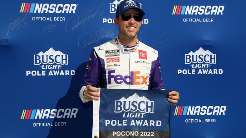 Jul 23, 2022; Long Pond, Pennsylvania, USA; NASCAR Cup Series driver Denny Hamlin poses with the pole award after winning the pole during practice and qualifying for the M&Ms Fan Appreciation 400 at Pocono Raceway. Mandatory Credit: Matthew OHaren-USA TODAY Sports