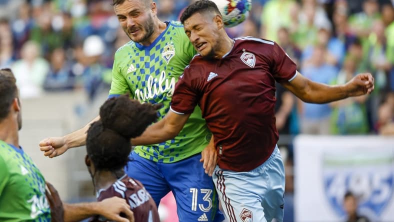 Jul 23, 2022; Seattle, Washington, USA; Seattle Sounders FC forward Jordan Morris (13) jumps for a corner kick against Colorado Rapids midfielder Bryan Acosta (21) during the first half at Lumen Field. Mandatory Credit: Joe Nicholson-USA TODAY Sports