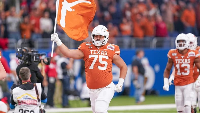 Dec 31, 2019; San Antonio, Texas, USA;  Texas Longhorns offensive lineman Junior Angilau (75) carries a flag onto the field before the game against the Utah Utes at the Alamodome. Mandatory Credit: Daniel Dunn-USA TODAY Sports