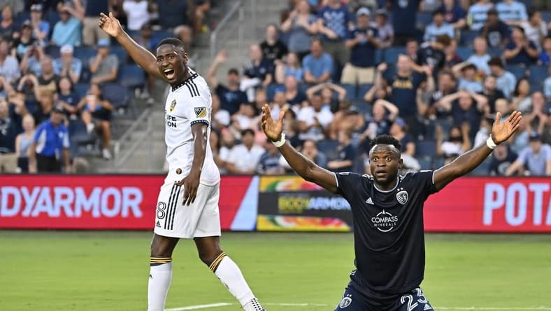 Aug 6, 2022; Kansas City, Kansas, USA; Sporting Kansas City forward William Agada (23) reacts after his header for a goal during the first half against Los Angeles Galaxy midfielder Marco Delgado (8) at Children's Mercy Park. Mandatory Credit: Peter Aiken-USA TODAY Sports