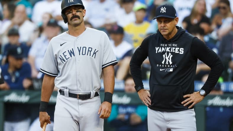 Aug 8, 2022; Seattle, Washington, USA; New York Yankees designated hitter Matt Carpenter (left) reacts while manager Aaron Boone (right) watches after a foul ball struck his foot during the first inning against the Seattle Mariners at T-Mobile Park. Mandatory Credit: Joe Nicholson-USA TODAY Sports