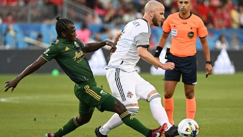 Aug 13, 2022; Toronto, Ontario, CAN;  Toronto FC midfielder Michael Bradley (4) passes the ball away from Portland Timbers midfielder Diego Chara (21) in the first half at BMO Field. Mandatory Credit: Dan Hamilton-USA TODAY Sports