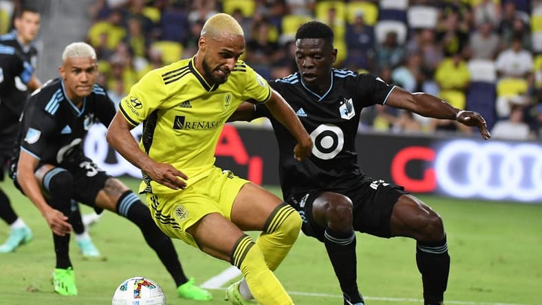 Aug 14, 2022; Nashville, Tennessee, USA; Nashville SC midfielder Hany Mukhtar (10) handles the ball against Minnesota United FC defender Bakaye Dibassy (12) during the second half at Geodis Park. Mandatory Credit: Christopher Hanewinckel-USA TODAY Sports