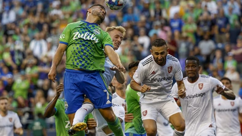 Aug 14, 2022; Seattle, Washington, USA; Seattle Sounders FC midfielder Cristian Roldan (7) jumps to head a corner kick against Real Salt Lake defender Jasper Loffelsend (28) and forward Justin Meram (right) during the first half at Lumen Field. Mandatory Credit: Joe Nicholson-USA TODAY Sports