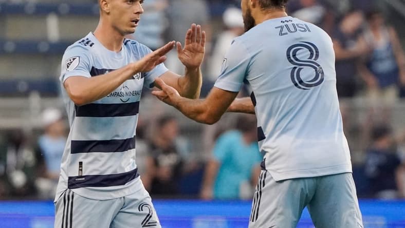 Aug 21, 2022; Kansas City, Kansas, USA; Sporting Kansas City midfielder Erik Thammy (26) celebrates with defender Graham Zusi (8) after scoring against the Portland Timbers during the first half of the match at Children's Mercy Park. Mandatory Credit: Denny Medley-USA TODAY Sports
