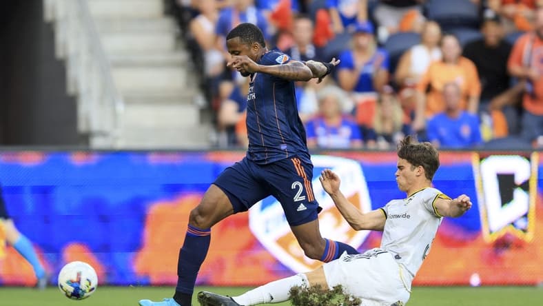Aug 27, 2022; Cincinnati, Ohio, USA;  Columbus Crew SC defender Josh Williams (right) attempts to tackle against FC Cincinnati defender Alvas Powell (2) in the first half at TQL Stadium. Mandatory Credit: Aaron Doster-USA TODAY Sports