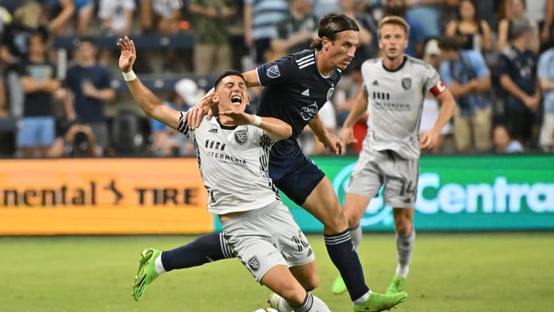 Aug 27, 2022; Kansas City, Kansas, USA; San Jose Earthquakes forward Cristian Espinoza (10) gets pulled down from behind by Sporting Kansas City defender Ben Sweat (2)during the first half at Children's Mercy Park. Mandatory Credit: Peter Aiken-USA TODAY Sports