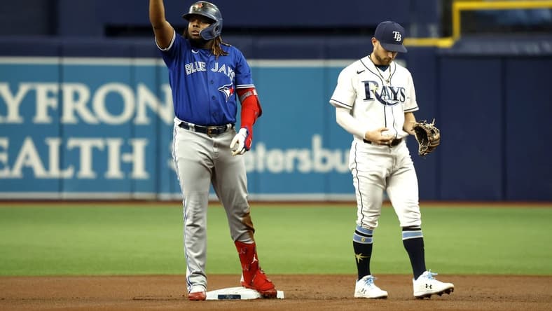Aug 2, 2022; St. Petersburg, Florida, USA; Toronto Blue Jays first baseman Vladimir Guerrero Jr. (27) celebrates after hitting a double as Tampa Bay Rays second baseman Brandon Lowe (8) looks down during the first inning at Tropicana Field. Mandatory Credit: Kim Klement-USA TODAY Sports