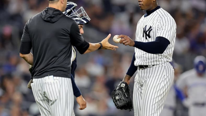 Aug 19, 2022; Bronx, New York, USA; New York Yankees relief pitcher Aroldis Chapman (54) hands the ball to manager Aaron Boone (17) after being taken out of the game against the Toronto Blue Jays during the ninth inning at Yankee Stadium. Mandatory Credit: Brad Penner-USA TODAY Sports