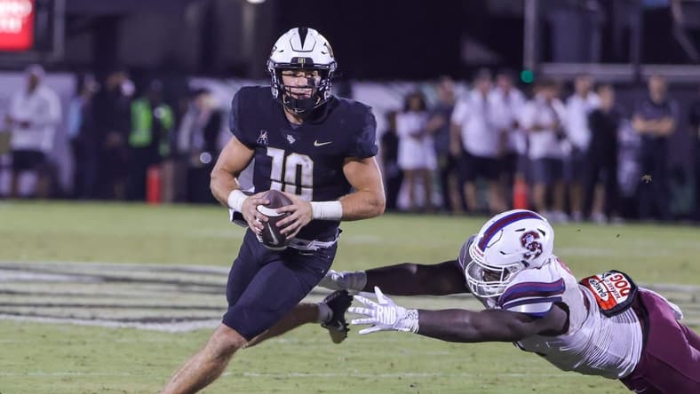 Sep 1, 2022; Orlando, Florida, USA; UCF Knights quarterback John Rhys Plumlee (10) carries the ball as South Carolina State Bulldogs defensive lineman Jeblonski Green Jr. (34) moves in during the second half at FBC Mortgage Stadium. Mandatory Credit: Mike Watters-USA TODAY Sports