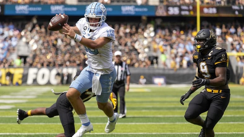 Sep 3, 2022; Boone, North Carolina, USA; North Carolina Tar Heels quarterback Drake Maye (10) dives into the end zone for the two point conversion attempt pursued by Appalachian State Mountaineers linebacker Nick Hampton (9) during the second half at Kidd Brewer Stadium. Mandatory Credit: Jim Dedmon-USA TODAY Sports