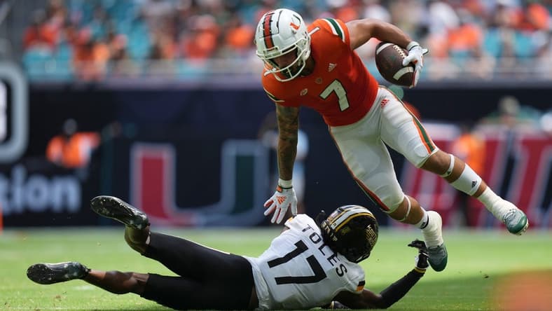 Sep 10, 2022; Miami Gardens, Florida, USA; Miami Hurricanes wide receiver Xavier Restrepo (7) leaps away from the tackle attempt of Southern Miss Golden Eagles defensive back Brendan Toles (17) during the second half at Hard Rock Stadium. Mandatory Credit: Jasen Vinlove-USA TODAY Sports