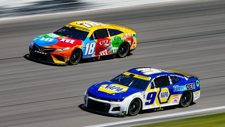 Sep 11, 2022; Kansas City, Kansas, USA; NASCAR Cup Series driver Chase Elliott (9) leads driver Kyle Busch (18) during the Hollywood Casino 400 at Kansas Speedway. Mandatory Credit: Jay Biggerstaff-USA TODAY Sports