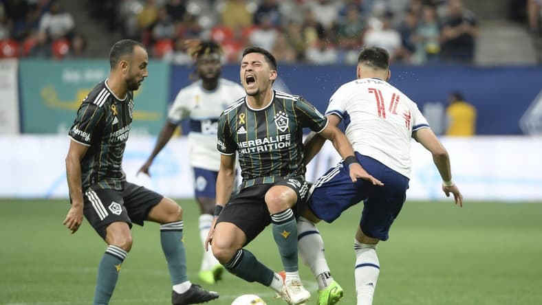 Sep 14, 2022; Vancouver, British Columbia, CAN;  Vancouver Whitecaps FC defender Luis Martins (14) collides with LA Galaxy midfielder Marco Delgado (8) during the first half at BC Place. Mandatory Credit: Anne-Marie Sorvin-USA TODAY Sports