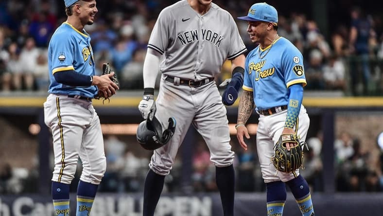 Sep 16, 2022; Milwaukee, Wisconsin, USA; New York Yankees center fielder Aaron Judge (99) talks to Milwaukee Brewers shortstop Willy Adames (27) and second baseman Kolten Wong (16) during a pause in the game in the second inning at American Family Field. Mandatory Credit: Benny Sieu-USA TODAY Sports