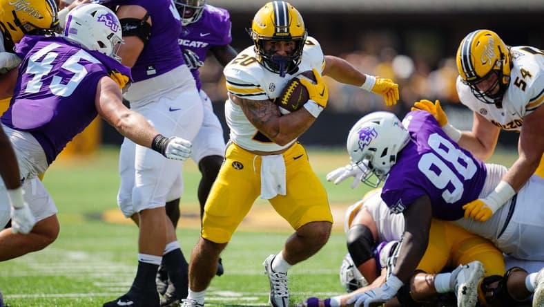 Sep 17, 2022; Columbia, Missouri, USA; Missouri Tigers running back Cody Schrader (20) runs the ball against Abilene Christian Wildcats defensive lineman Jordan Paup (45) and defensive lineman David Oke (98) during the first half at Faurot Field at Memorial Stadium. Mandatory Credit: Jay Biggerstaff-USA TODAY Sports