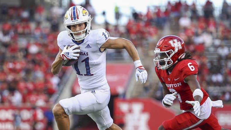 Sep 17, 2022; Houston, Texas, USA; Kansas Jayhawks wide receiver Luke Grimm (11) runs with the ball and scores a touchdown as Houston Cougars defensive back Jayce Rogers (6) defends during the second quarter at TDECU Stadium. Mandatory Credit: Troy Taormina-USA TODAY Sports