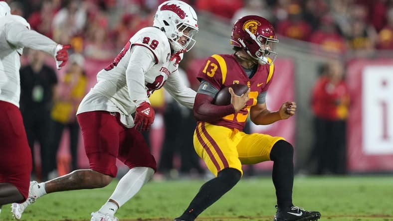 Sep 17, 2022; Los Angeles, California, USA; Southern California Trojans quarterback Caleb Williams (13) is pressured by Fresno State Bulldogs defensive end David Perales (99) in the first half at United Airlines Field at Los Angeles Memorial Coliseum. Mandatory Credit: Kirby Lee-USA TODAY Sports