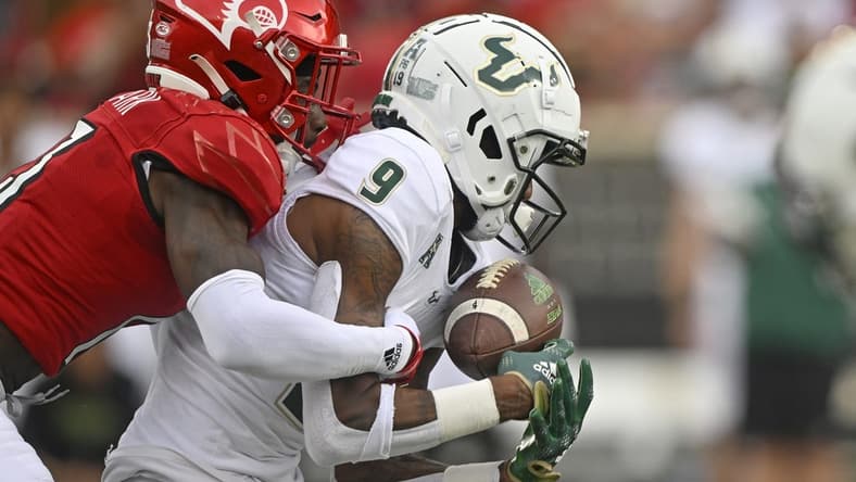 Sep 24, 2022; Louisville, Kentucky, USA;  South Florida Bulls receiver Yusuf Terry (9) catches a pass under the pressure of Louisville Cardinals defensive back Kei'Trel Clark (13) during the second quarter at Cardinal Stadium. Mandatory Credit: Jamie Rhodes-USA TODAY Sports