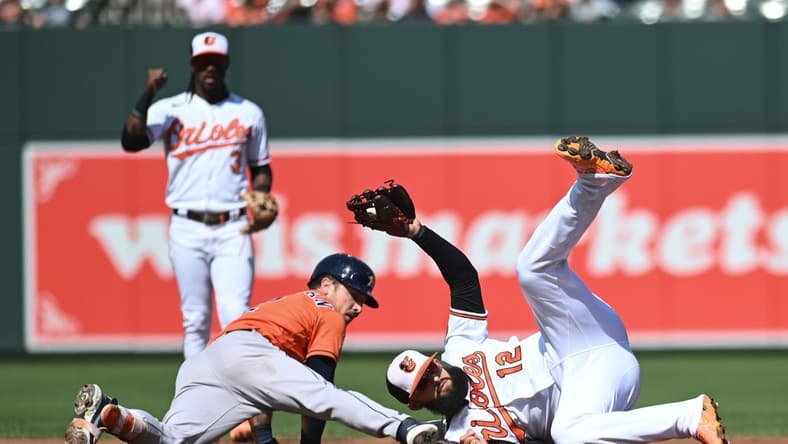 Sep 25, 2022; Baltimore, Maryland, USA;  Baltimore Orioles second baseman Rougned Odor (12) rolls after tagging out a sliding Houston Astros third baseman Alex Bregman (2) in the second inning at Oriole Park at Camden Yards. Mandatory Credit: Tommy Gilligan-USA TODAY Sports
