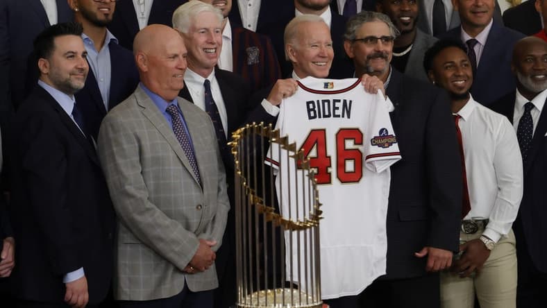 Sep 26, 2022; Washington, District of Columbia, US; President Joe Biden (M) holds a gift jersey while posing for a picture with (L-R) Atlanta Braves general manager and president of baseball operations Alex Anthopoulos, Braves manager Brian Snitker, and Braves chairman Terry McGuirk (M-L) during a ceremony honoring the 2021 World Series champion Braves in the East Room at The White House. Mandatory Credit: Geoff Burke-USA TODAY Sports