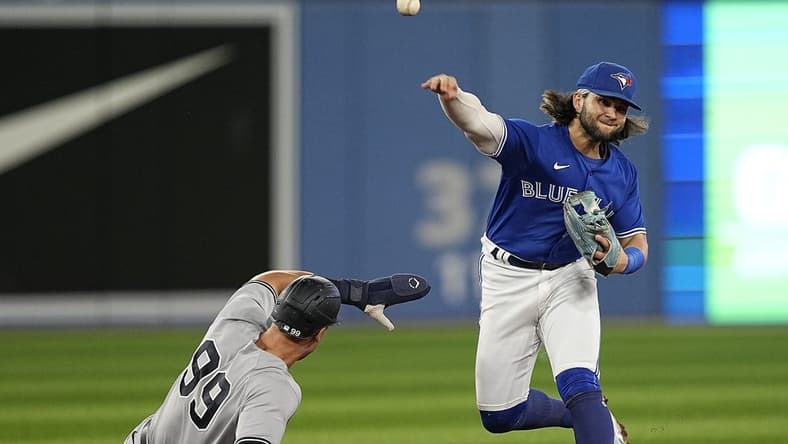 Sep 26, 2022; Toronto, Ontario, CAN; Toronto Blue Jays shortstop Bo Bichette (right) throws to first base after forcing New York Yankees right fielder Aaron Judge (99) out at second base during the third inning at Rogers Centre. Mandatory Credit: John E. Sokolowski-USA TODAY Sports