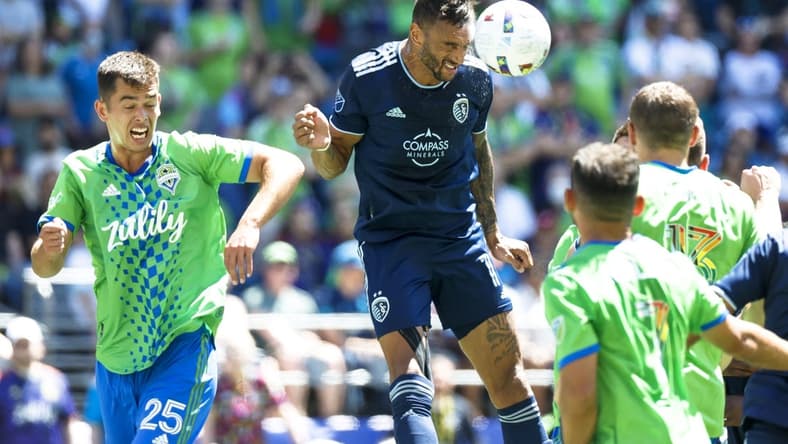 Jun 25, 2022; Seattle, Washington, USA; Sporting Kansas City forward Khiry Shelton (11) heads away a corner kick against Seattle Sounders FC defender Jackson Ragen (25) during the first half at Lumen Field. Mandatory Credit: Joe Nicholson-USA TODAY Sports