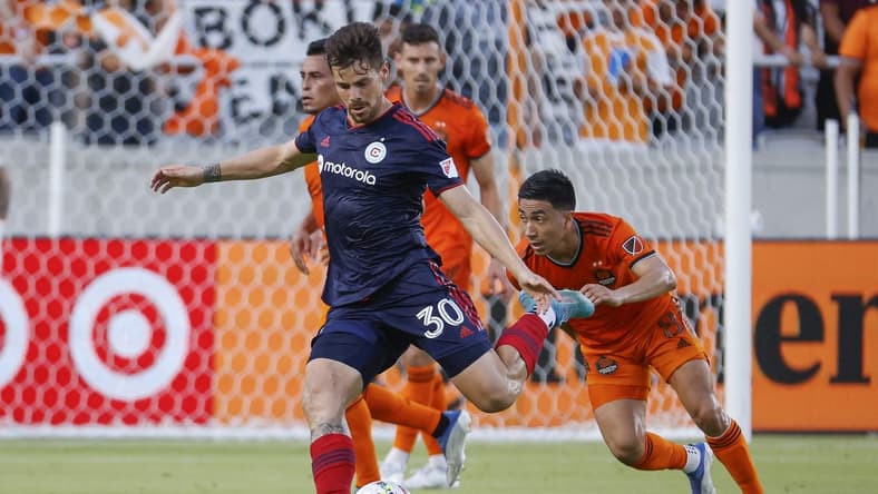Jun 25, 2022; Houston, Texas, USA;  Chicago Fire midfielder Gaston Gimenez (30) kicks the ball as Houston Dynamo FC midfielder Memo Rodriguez (8) defends during the first half at PNC Stadium. Mandatory Credit: Troy Taormina-USA TODAY Sports