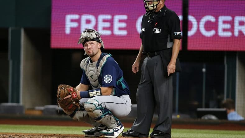 Aug 12, 2022; Arlington, Texas, USA; Seattle Mariners catcher Cal Raleigh (29) looks to the dugout as umpire Jerry Meals (41) looks on in the second inning against the Texas Rangers at Globe Life Field. Mandatory Credit: Tim Heitman-USA TODAY Sports