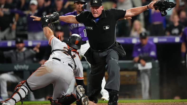 Sep 20, 2022; Denver, Colorado, USA; MLB home plate umpire Ted Barrett (65) signals safe towards San Francisco Giants catcher Joey Bart (21) in the eighth inning against the Colorado Rockies at Coors Field. Mandatory Credit: Ron Chenoy-USA TODAY Sports