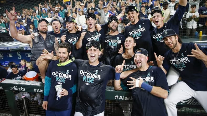 Sep 30, 2022; Seattle, Washington, USA; Seattle Mariners players and staff, including relief pitcher Matthew Boyd (first row, second from left) and catcher Cal Raleigh (first row second from right) celebrate in the dugout following a 2-1 victory against the Oakland Athletics to clinch a wild card playoff berth at T-Mobile Park. Mandatory Credit: Joe Nicholson-USA TODAY Sports