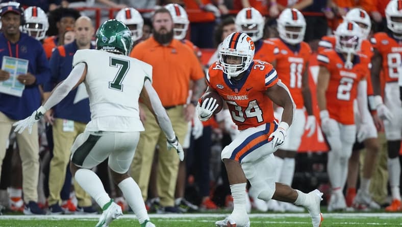 Oct 1, 2022; Syracuse, New York, USA; Syracuse Orange running back Sean Tucker (34) runs with the ball with Wagner Seahawks defensive back Coby Calvin (7) defending during the first half at JMA Wireless Dome. Mandatory Credit: Gregory Fisher-USA TODAY Sports