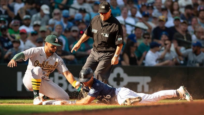 Oct 1, 2022; Seattle, Washington, USA; Seattle Mariners second baseman Adam Frazier (26) beats the throw to Oakland Athletics third baseman Vimael Machin (31) to steal third base during the seventh inning at T-Mobile Park. Mandatory Credit: Steven Bisig-USA TODAY Sports