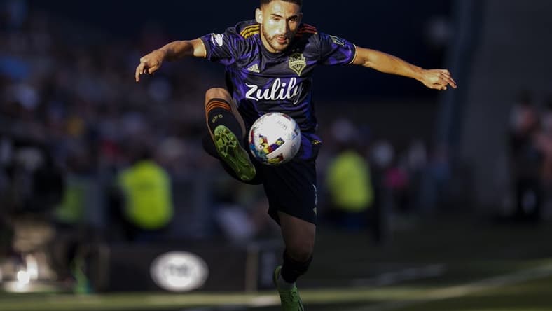 Oct 2, 2022; Kansas City, Kansas, USA; Seattle Sounders midfielder Cristian Roldan (7) leaps to receive a pass during the second half against the Sporting Kansas City at Children's Mercy Park. Mandatory Credit: Jay Biggerstaff-USA TODAY Sports