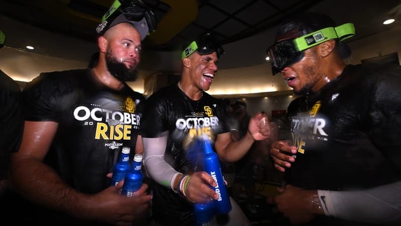 Oct 2, 2022; San Diego, California, USA; San Diego Padres right fielder Juan Soto (center) celebrates in the clubhouse with relief pitcher Luis Garcia (left) and center fielder Jose Azocar (right) following the game against the Chicago White Sox after clinching a playoff berth at Petco Park. Mandatory Credit: Orlando Ramirez-USA TODAY Sports