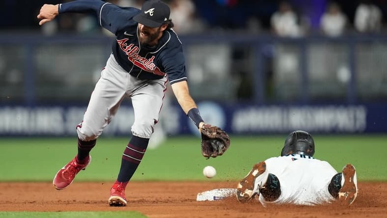 Oct 3, 2022; Miami, Florida, USA; Miami Marlins second baseman Jon Berti (5) steals second base in the first inning as Atlanta Braves shortstop Dansby Swanson (7) reaches for the ball at loanDepot Park. Mandatory Credit: Jim Rassol-USA TODAY Sports