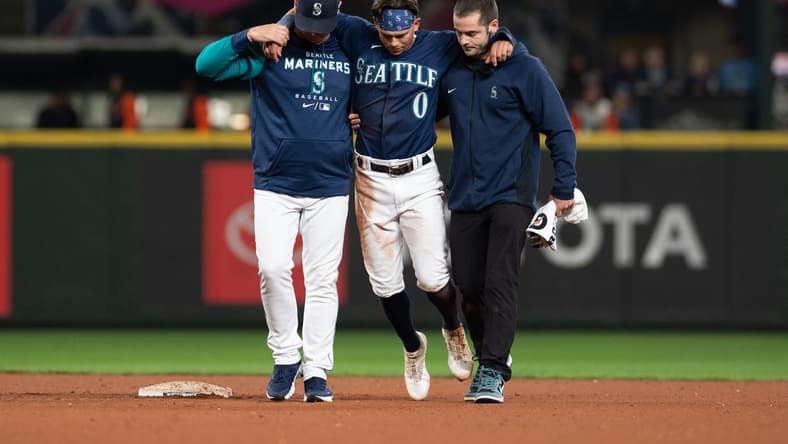 Oct 3, 2022; Seattle, Washington, USA; Seattle Mariners assistant athletic trainer Kevin Orloski and head coach Scott Servais help right fielder Sam Haggerty (0) off the field after Haggerty was injured sliding into second base during the ninth inning against the Detroit Tigers at T-Mobile Park. Detroit defeated Seattle 4-3. Mandatory Credit: Steven Bisig-USA TODAY Sports